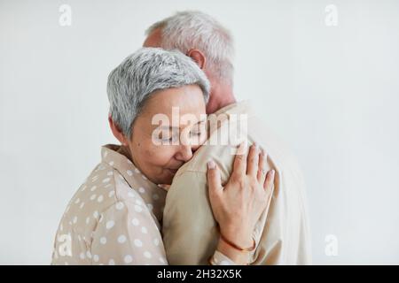 Donna anziana con capelli grigi godendo la danza con il marito sullo sfondo bianco Foto Stock