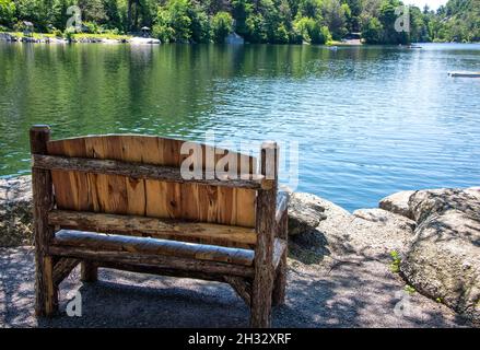 Panca vuota di legno sulla costa del lago Mohonk, nella parte settentrionale dello stato di New York. Foto Stock