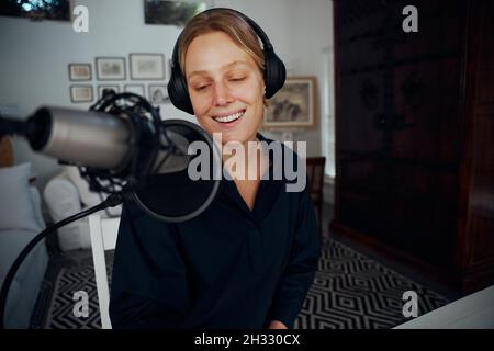 Podcaster femmina caucasico che lavora da casa registrando nuove serie Foto Stock