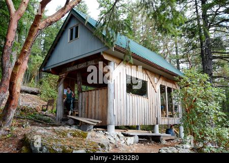 Una donna escursionista al rifugio da campeggio Manzanita Hut nella foresta pluviale temperata, sul Sunshine Coast Trail, vicino a Lund, British Columbia, Canada. Foto Stock