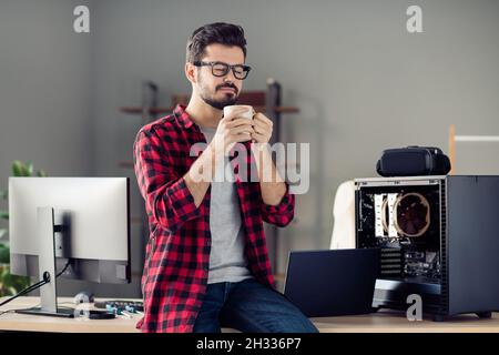 Ritratto di bello attraente ragazzo sognante intelligente seduto sul tavolo bere latte buon inizio giorno al posto di lavoro stazione al coperto Foto Stock