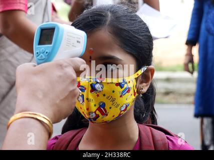 Bangalore, India. 25 ottobre 2021. Un insegnante controlla la temperatura corporea di uno studente in una scuola a Bangalore, India, 25 ottobre 2021. Gli studenti di grado da 1 a 5 a Bangalore tornarono a scuola con le precauzioni COVID-19. Credit: Str/Xinhua/Alamy Live News Foto Stock