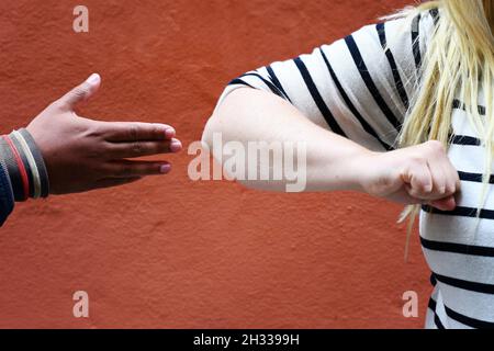 Concetto di confusione di come fare saluti nella nuova normalità dopo la pandemia del coronavirus: Dire ciao scuotendo le mani o faremo un gomito bump? Foto Stock
