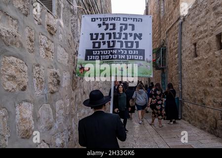 Un ebreo religioso ha un segno che dice 'Una vita beata è solo senza internet e film' mentre cammina attraverso un vicolo nel quartiere ebraico nella città vecchia di Gerusalemme Israele. Le comunità di Haredi hanno di solito la tecnologia moderna come internet e gli smartphone. Il loro ragionamento è che l'immensa quantità di informazioni può essere corrompente, e con la capacità di utilizzare Internet senza alcuna osservazione da parte della comunità può portare a individuazione. Foto Stock