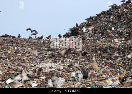 Persone raccolta rifiuti pick i rifiuti non biodegradabili da utilizzare per l'industria di riciclaggio in discarica sito a Dhaka molte persone vivono raccogliendo rifiuti dalle montagne di rifiuti che è generato quotidianamente, soprattutto dalla capitale di Dhaka. Il Bangladesh, l'ottavo paese più popoloso del mondo, ha attualmente un grave problema di inquinamento dovuto alla produzione di rifiuti solidi nelle aree urbane del Bangladesh, che equivale a circa 25,000 tonnellate al giorno. La città di Dhaka produce un quarto di tutti i rifiuti urbani del paese. Si prevede che i rifiuti solidi urbani totali aumentino fino a 47,000 tonnellate per Foto Stock