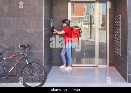 Una ragazza consegna ciclista che suona la campana dell'interfono Foto Stock