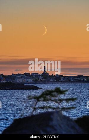 Luna di Crescent che sorge su Alnes durante un caldo tramonto Foto Stock