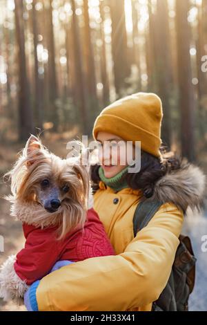 Bella ragazza caucasica con un cane. Carina ragazza felice con il suo cane sono a piedi nel parco in una giornata soleggiata autunno. Razza Crested cinese. Primo piano. Vertica Foto Stock