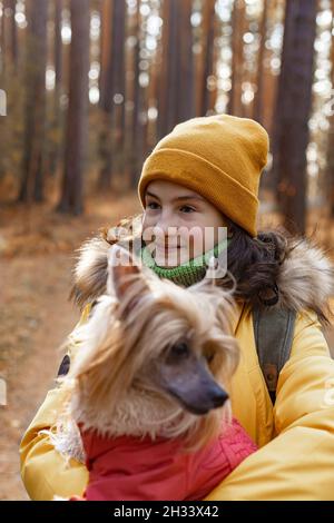 Bella ragazza caucasica con un cane. Carina ragazza felice con il suo cane sono a piedi nel parco in una giornata soleggiata autunno. Razza Crested cinese. Primo piano. Vertica Foto Stock