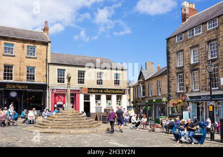 Persone nella storica Piazza del mercato e Market Cross Market Place Alnwick centro città Alnwick Northumberland Northumbria Inghilterra Regno Unito GB Europa Foto Stock