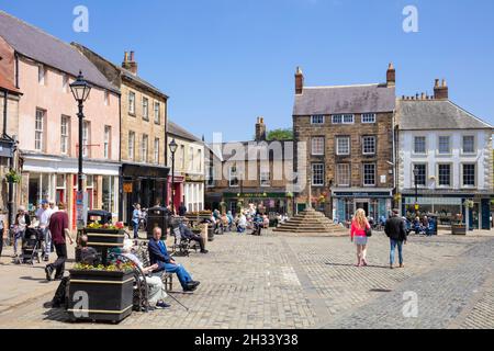 Persone nella storica Piazza del mercato e Market Cross Market Place Alnwick centro città Alnwick Northumberland Northumbria Inghilterra Regno Unito GB Europa Foto Stock