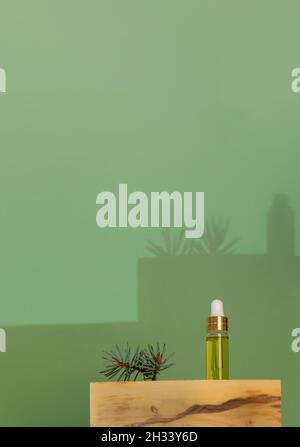 Aromaterapia creativa di Natale e spa composizione minimalista con una piccola bottiglia di vetro di olio essenziale di abete rosso e twig su bello stand di legno di bosso e. Foto Stock