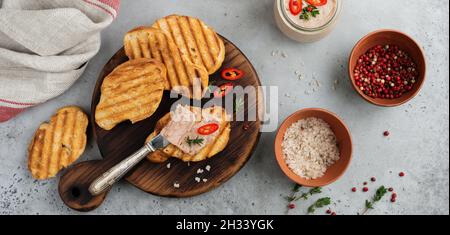 Piatto di pollo fatto in casa di fegato con pepe rosso, rametti di timo e fette di pane tostate su vecchio asse di legno su cemento grigio o sfondo di pietra. Selez Foto Stock