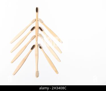 Spazzolini ecologici in bambù naturale per la cura dentale, igiene personale, disposti come albero di Natale su bianco. Concetto creativo di Natale minimo. PLASTI Foto Stock
