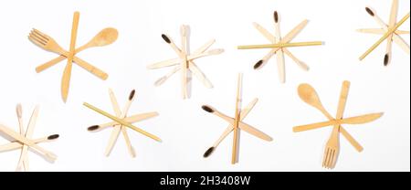 Banner creativo natalizio con motivo di spazzolini ecologici in bambù e posate in legno disposte come fiocchi di neve su sfondo bianco. Senza plastica, Foto Stock
