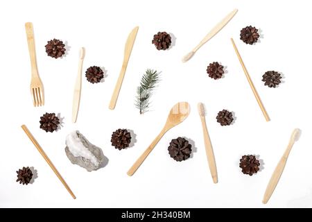 Natale creativo piatto disposizione di base eco-friendly spazzolini in bambù, posate in legno, coni di pino, abete twig e pietra su sfondo bianco. Plastica Foto Stock