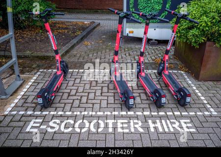 E-Scooters parcheggiato in un parcheggio designato in attesa del loro prossimo noleggio. Foto Stock