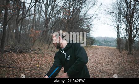 Giovane atletico che gioca a disc golf nei boschi durante l'inverno Foto Stock