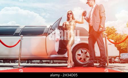 Autista aiutando vip donna o star fuori di limo sul tappeto rosso Foto Stock