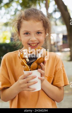 La bambina sta gustando un waffle belga Foto Stock