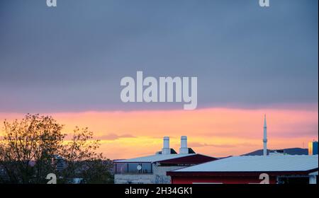 Tramonto cielo in giornata nuvolosa a Bursa con case e tetti con minareto di una moschea locale e stazioni radio. Foto Stock