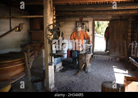 Un fabbro lavora con un ferro e un incudine nel negozio di fabbri al museo di storia vivente El Rancho de las Golondrinas vicino a Santa Fe, New Mexico. Foto Stock