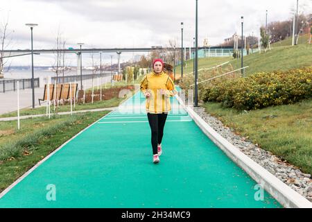 giovane donna che fa jogging nel parco autunnale lungo il lungofirio Foto Stock