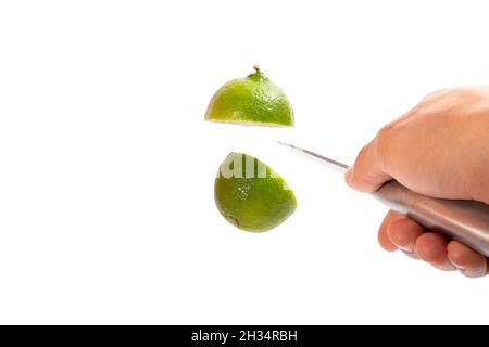 il limone viene tagliato nell'aria da un coltello isolato su sfondo bianco. Foto Stock