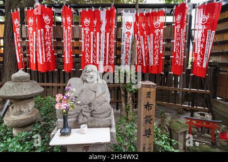 Una statua di Hotei, uno dei sette dei della Fortuna al tempio Toyokawa Inari Betsuin ad Asakusa, Tokyo, Giappone. Il tempio buddista fa parte della setta Soto Zen e sancisce la divinità Toyokawa Dakinishinten, ma è anche noto per le migliaia di statue di volpi. Foto Stock