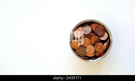 Selezione assortita di penny americani di uso corrente in una tazza di cromo su uno sfondo bianco con spazio di copia; centesimo degli Stati Uniti; monete, denaro, valuta. Foto Stock