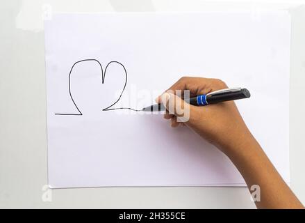 Top close up sopra la foto vista dall'alto del bambino di destra che tiene la penna di legno che inizia a disegnare un'immagine isolato sfondo bianco di carta colore Foto Stock