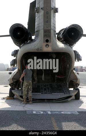 Un ingegnere di volo insieme ai soldati della Bravo Company, 1° Battaglione, 171° Regiment Aviazione, scarica il carico e l'attrezzatura a Camp Buehring, Kuwait. Foto Stock