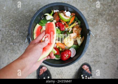 Rifiuti domestici per compost da frutta e verdura. Donna getta immondizia. Foto Stock