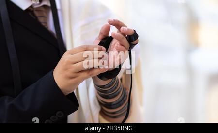 03-10-2021. gerusalemme-israele. Un primo piano di un ragazzo di bar mitzvah ebraico, indossando una camicia bianca e un vestito nero, ha messo il tefillin per la prima volta nel Th Foto Stock