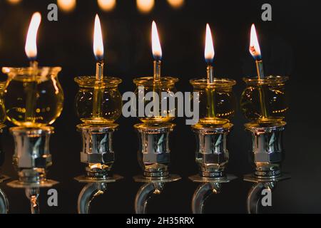 Le candele di Hanukkah sono illuminate in una menora decorata in argento, su uno sfondo nero della notte - la festa ebraica di Hanukkah Foto Stock