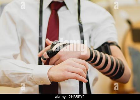 gerusalemme-israele. 24-01-2020. Un primo piano di un ragazzo di bar mitzvah ebreo, con una camicia bianca e una cravatta rossa. Indossando un tefillin per la prima volta in un Foto Stock