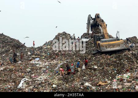 Persone raccolta rifiuti pick i rifiuti non biodegradabili da utilizzare per l'industria di riciclaggio in discarica sito a Dhaka molte persone vivono raccogliendo rifiuti dalle montagne di rifiuti che è generato quotidianamente, soprattutto dalla capitale di Dhaka. Il Bangladesh, l'ottavo paese più popoloso del mondo, ha attualmente un grave problema di inquinamento dovuto alla produzione di rifiuti solidi nelle aree urbane del Bangladesh, che equivale a circa 25,000 tonnellate al giorno. La città di Dhaka produce un quarto di tutti i rifiuti urbani del paese. Si prevede che i rifiuti solidi urbani totali aumentino fino a 47,000 tonnellate per Foto Stock