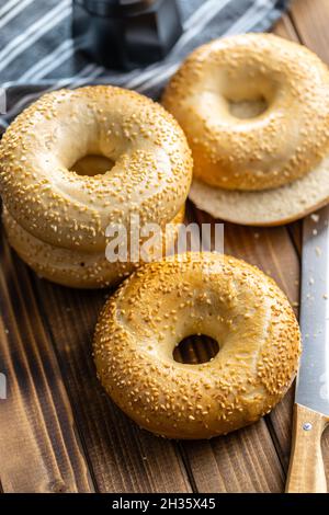 Bagel al forno con semi di sesamo su tavola di legno. Foto Stock