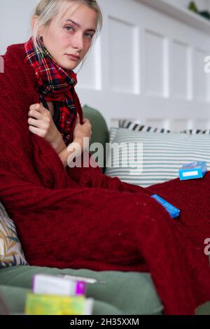 Donna malata con un cattivo sentimento avvolto in una coperta e sofferenza. Foto Stock