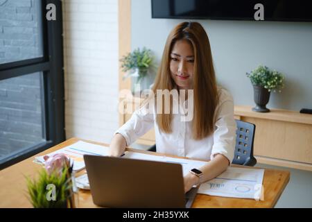 Foto di una splendida segretaria che lavora in ufficio, seduta alla scrivania di legno. Foto Stock