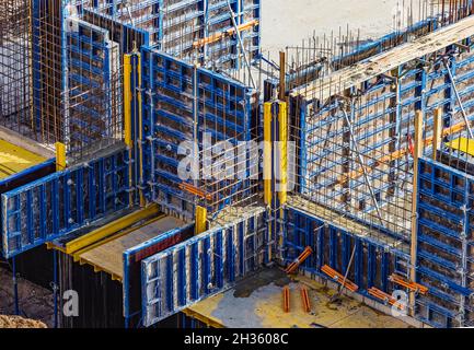 Casseforme installate e barre di ferro o di rinforzo per pareti divisorie in cemento armato nel cantiere di un grande edificio residenziale. Foto Stock