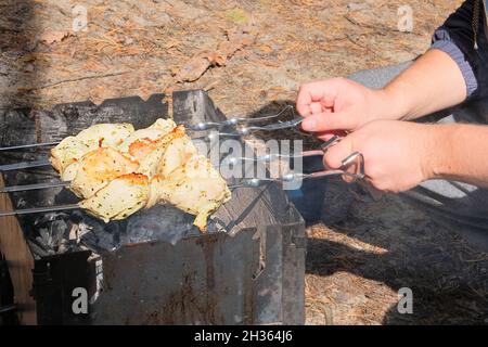 Il kebab shish è fritto all'aperto nella foresta autunnale. Frittura di carne alla griglia all'aperto. Pezzi fritti di spiedini di carne di pollo su carboni. Foto Stock