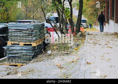 Riparazione del marciapiede della città in autunno. Pavimentazione in pietra per la riparazione dei sentieri. Foto Stock