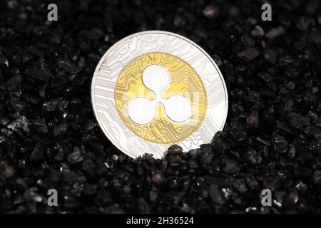 Ripple moneta XRP su sfondo di ghiaia nero. Denaro del blockchain di criptovaluta Foto Stock