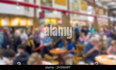 Immagine di sfondo sfocata di persone che mangiano in un'affollata area ristoro con ristoranti. Foto Stock