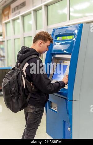 Giovane uomo con un backpage che acquista i biglietti da un distributore automatico in una stazione della metropolitana Foto Stock