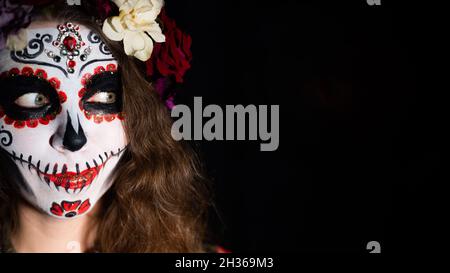 Donna in santa muerte trucco su sfondo nero. Ragazza che indossa tradizionale costume messicano di morte Santa per Halloween. Spazio di copia Foto Stock