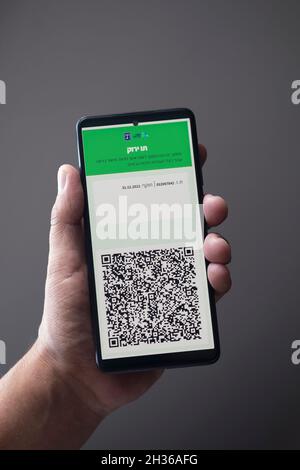Man possiede uno smartphone che mostra il codice QR del certificato COVID digitale Israeliano Green Pass che serve come prova che una persona è stata vaccinata contro COVID-19 e consente l'ingresso in strutture che devono conformarsi al programma governativo per contenere il coronavirus. Foto Stock