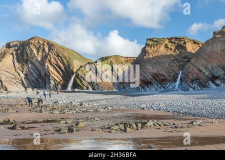 Persone sulla spiaggia vicino alle cascate di Sandymouth vicino a Bude Devon. Foto Stock