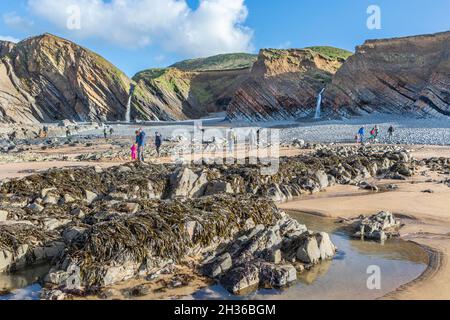 Persone sulla spiaggia vicino alle cascate di Sandymouth vicino a Bude Devon. Foto Stock